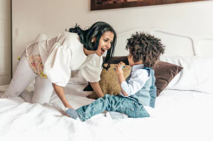 Woman and child playing on a bed with pillows